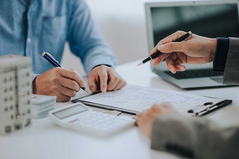 A pet owner reviews an insurance policy beside a dog and veterinary invoices at a kitchen table.